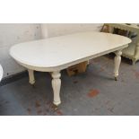 A cream painted dining table with rounded rectangular top above ring turned lobed legs and brass