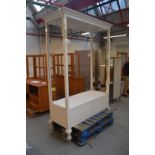 A large white painted shop display cabinet with moulded cornice above open sides,