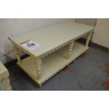 A painted two tier display table with shaped frieze, ring turned supports and peg feet,