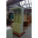 A pale green stained bookcase on cupboard,