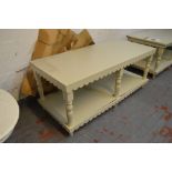 A painted two tier display table with shaped frieze, ring turned supports and peg feet,