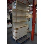 A shop fitting with glazed upper section containing three shelves above a base of twelve drawers,