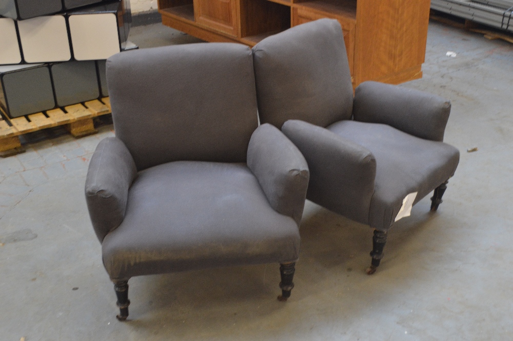 A pair of upholstered low armchairs raised on ebonised turned front legs.