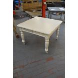 A white painted dining with rounded rectangular top above fluted turned legs to castors.