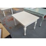 A white painted kitchen table with rounded rectangular top raised on ring turned legs to brass caps