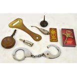 A large brass bottle opener, a pair of handcuffs, four small oil/grease containers,