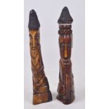 A pair of stained bone carvings each depicting a seated man with copper wire work hats,