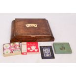 A burr walnut games box with hinged lid decorated with playing card suits,