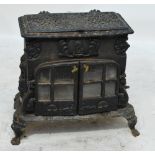 A cast iron shaped "gypsy" stove with pierced hinged top enclosing the hob,