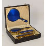A cased three piece base metal and blue guilloche enamel decorated dressing table set comprising a