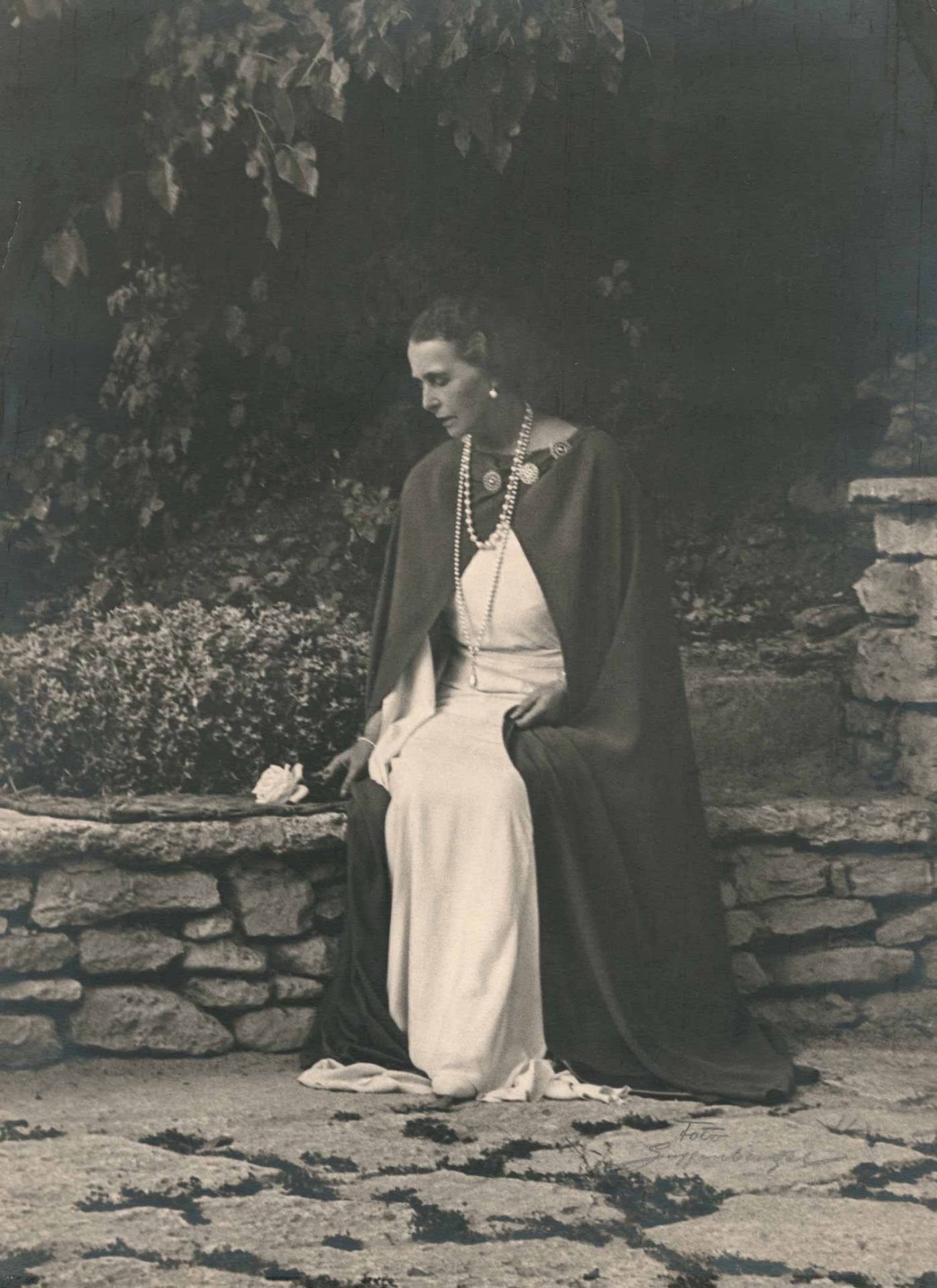 Maria, Königin von Rumänien (1875-1938). Portrait in ganzer Figur, auf einer Mauer im Park ihres