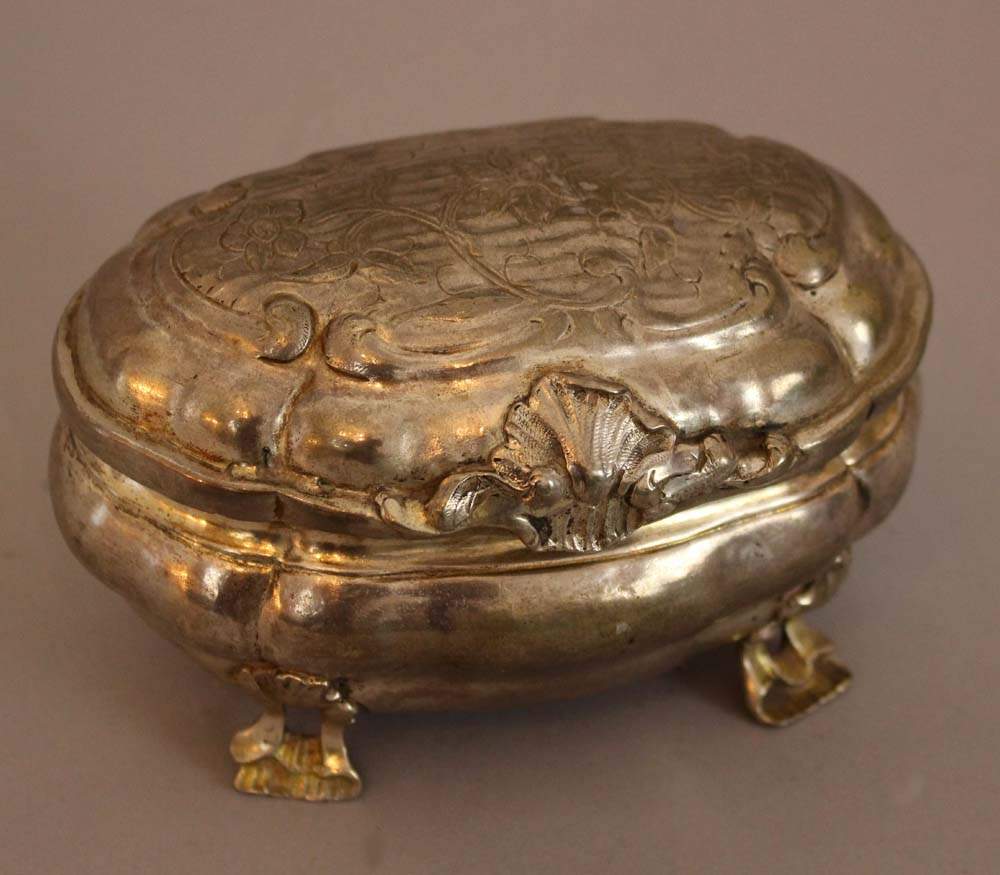 German baroque sugar box, oval shaped form on four floral shaped feet, stepped lid with decorated