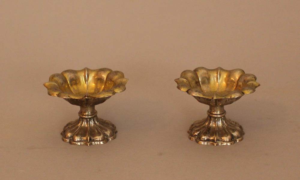 Pair of silver salt and pepper spenders in shaped floral design, each on one foot, with traces of