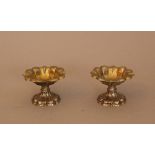 Pair of silver salt and pepper spenders in shaped floral design, each on one foot, with traces of