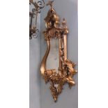 A CHIPPENDALE TRADITION GILDED CARTOUCHE SHAPED MIRROR WITH EXOTIC BIRD MOUNTS. LENGTH 44ins.