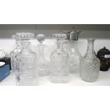 Six Glass Decanters of Various Shapes, to include a wine ewer with silver-plated handle and lid.