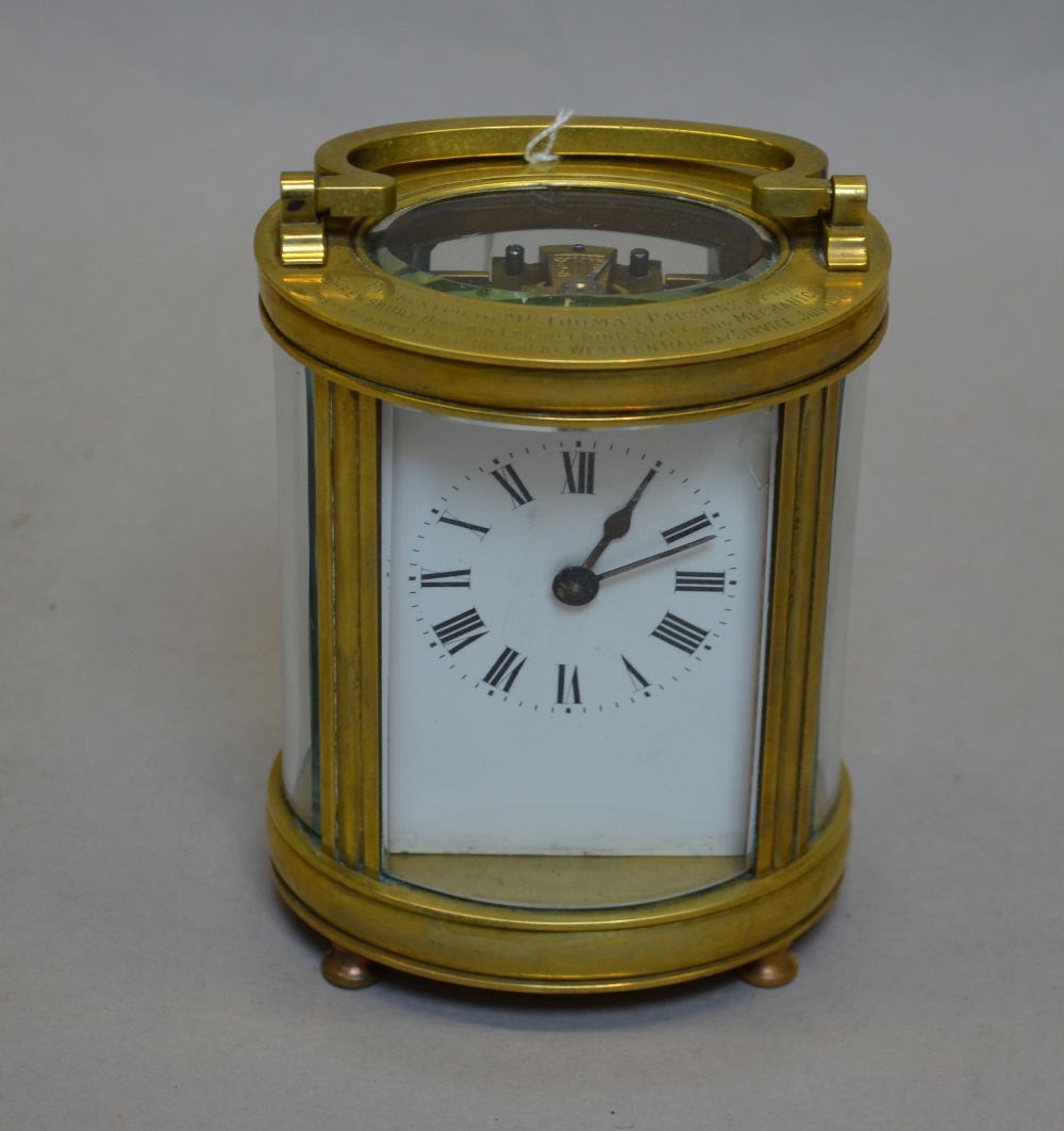 Oval-cased brass carriage clock engraved