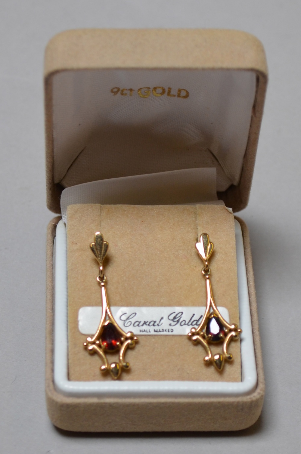 A pair of 9 catat gold earings with red stones.