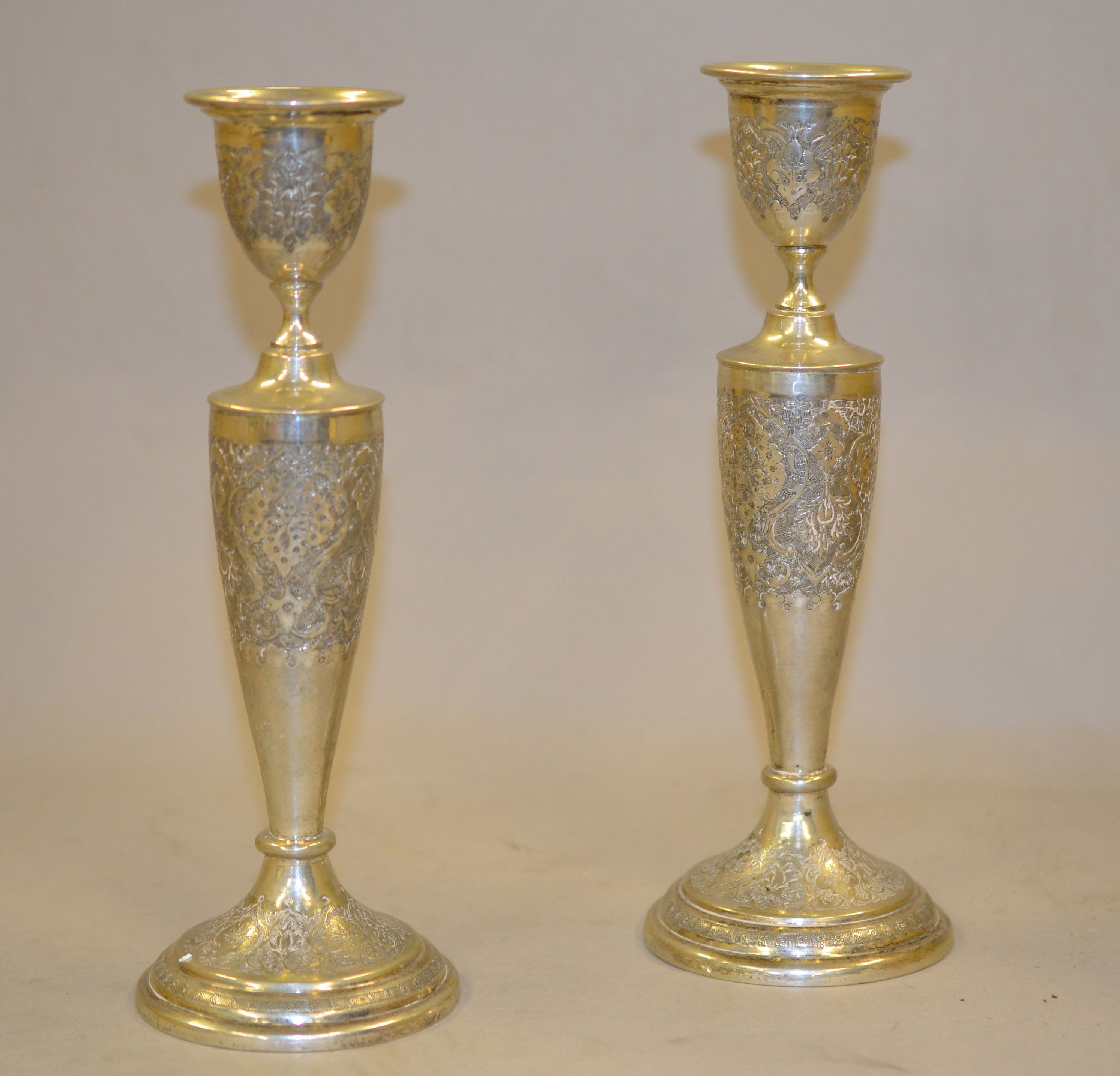 A pair of 'PERSIAN' white metal candlesticks with engraved decoration, approx 8.