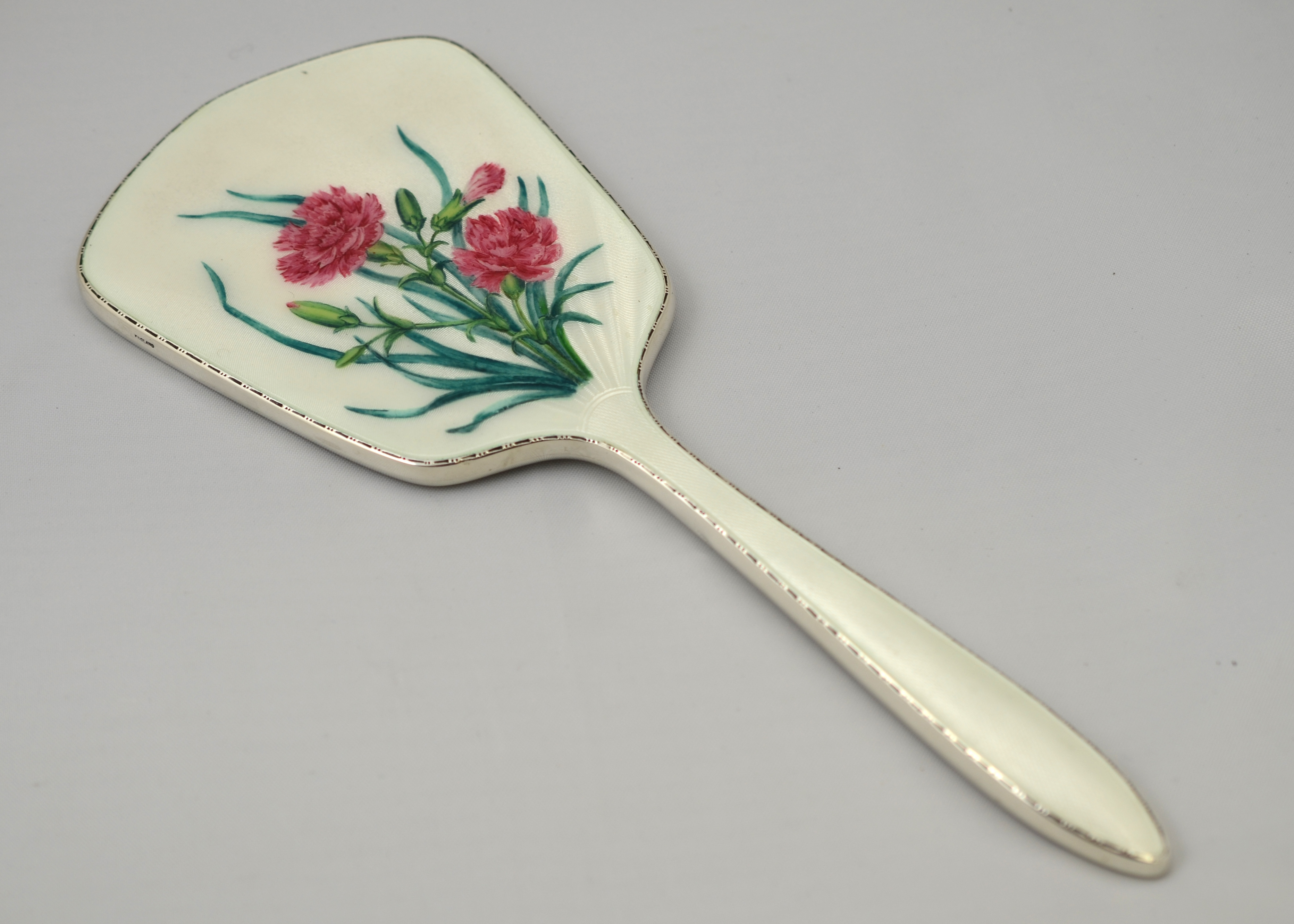 A Silver & enamelled hand mirror with floral decoration,