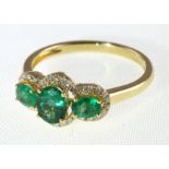 An 18ct H/M emerald & diamond three stone cluster ring, approx emerald weight 1.