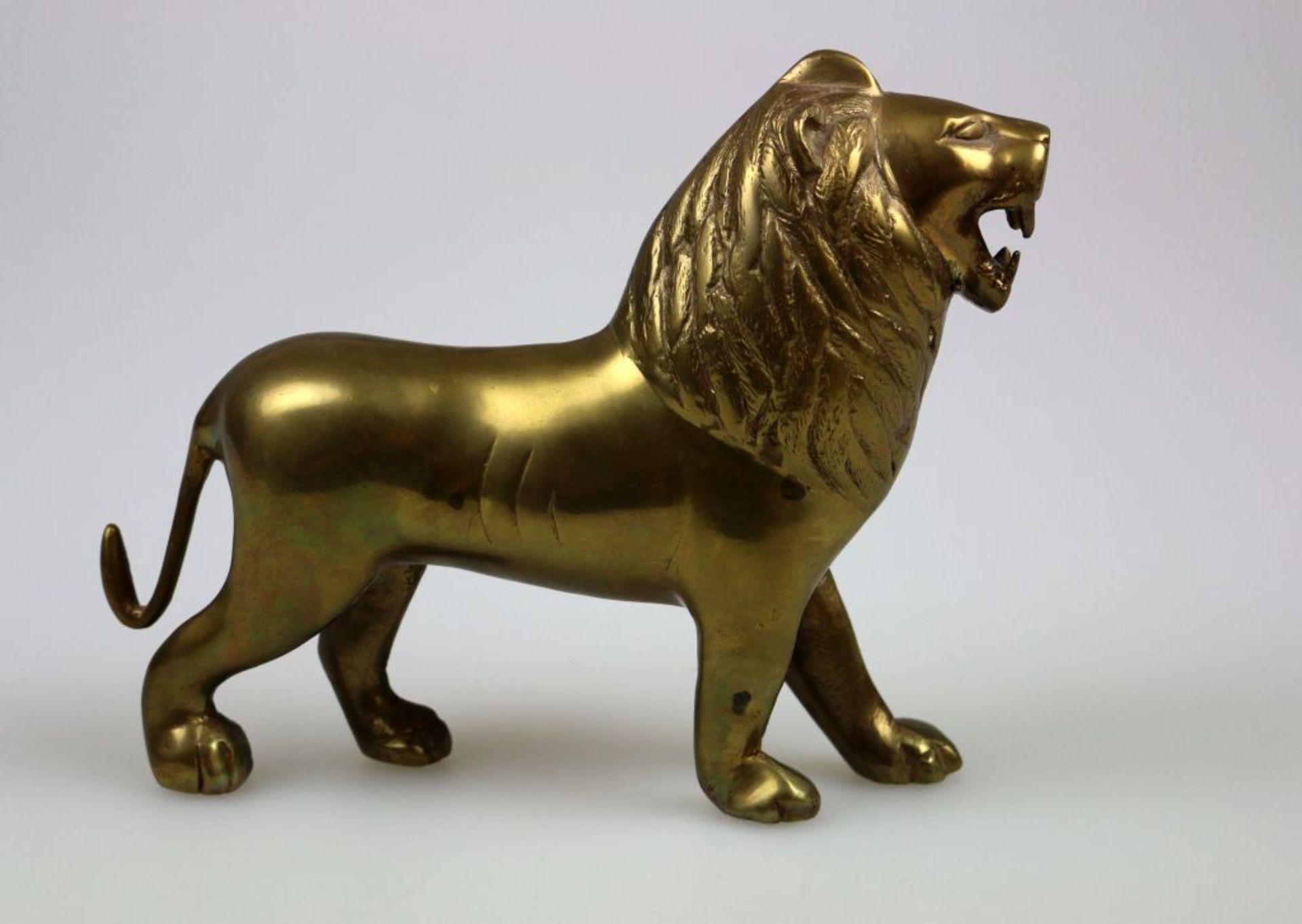 Stilisierte Löwenfigur aus vergoldetem Metall, Höhe 19 cm. StellenweiseAbnutzungserscheinungen.