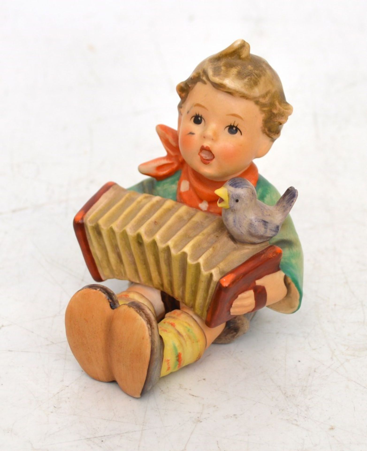 Musizierender Knabe  sitzender Jüngling mit Zieharmonika und kleinem Vogel, bunt bemalt, J. M.