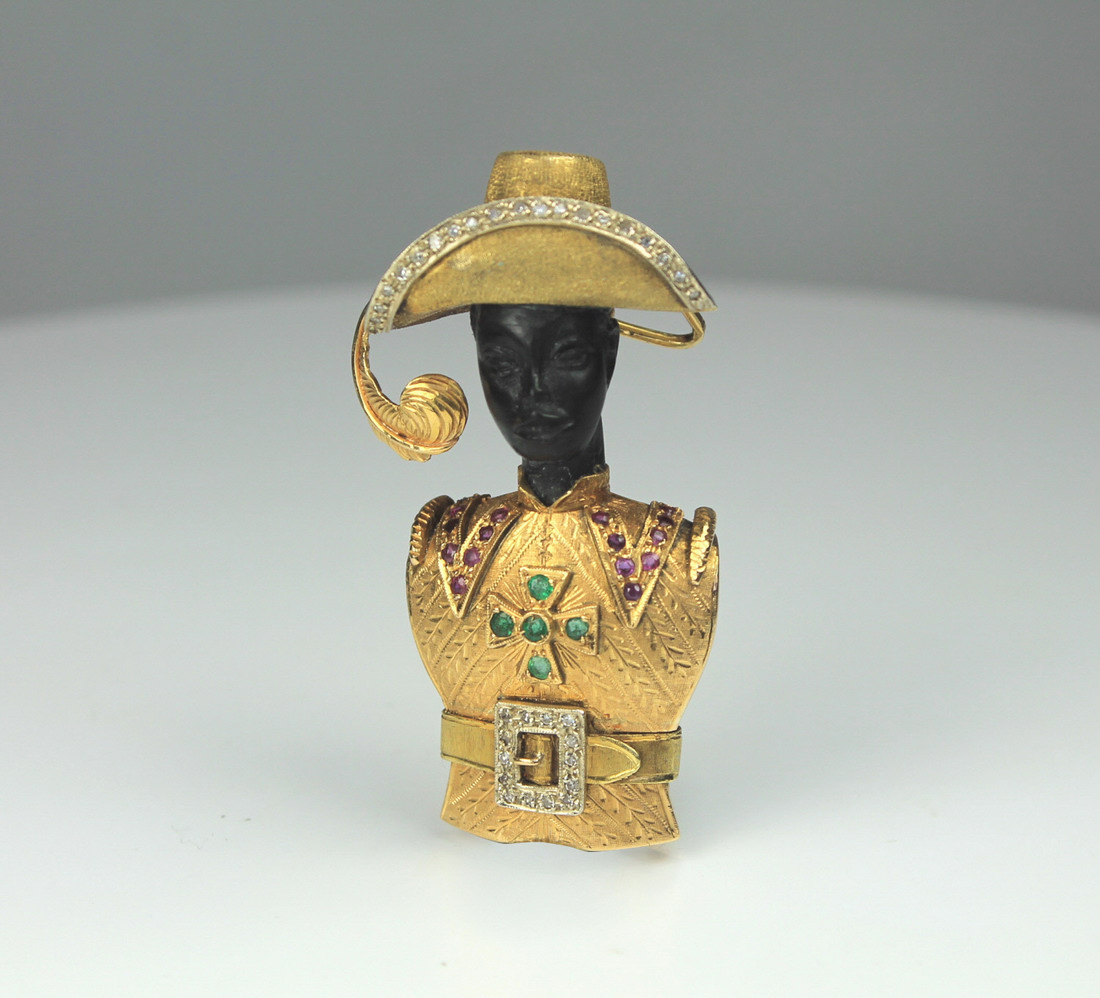 A ruby and emerald brooch depicting a Blackamoor, marked 18ct 750. The model wearing diamond set hat