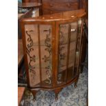 A 1940's serpentine display cabinet; wal