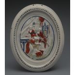 An 18th century pearlware oval plaque, in relief with theatrical figures, picked out in iron red and