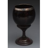 A 19th century century silver coloured metal mounted coconut cup, turned mahogany pedestal base,