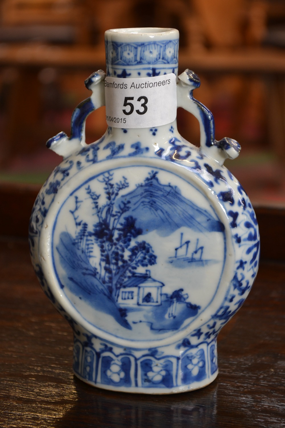 A Chinese moon flask, painted in underglaze blue with a house, boats and mountain, ruyi to