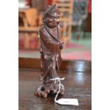 A Chinese hardwood carving, of a monk, he stands, a long string of prayer beads around his neck,