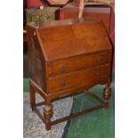 A 1940' s oak bureau, fall front enclosing pigeon holes, two long drawers, cup and cover forelegs.