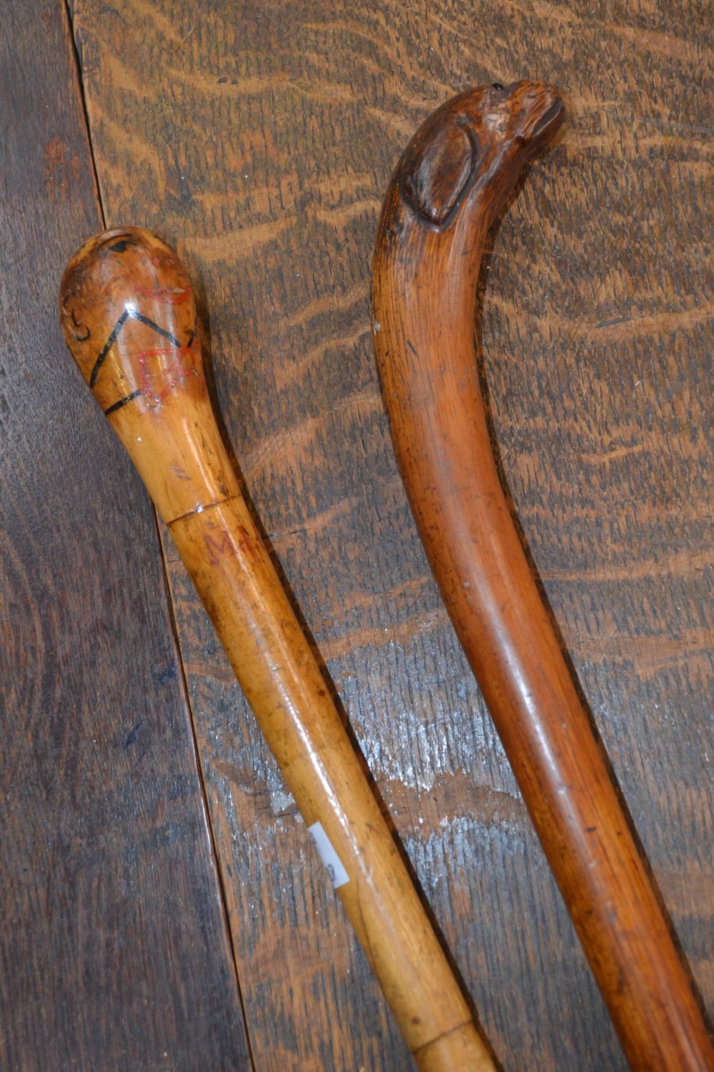 A 19th century novelty walking cane, the pommel carved as the head of a dog; another, painted as a