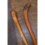 A 19th century novelty walking cane, the pommel carved as the head of a dog; another, painted as a