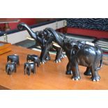 A pair of ebony coloured carved elephants with ivory tusks; four smaller (6)