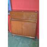 A retro bureau, fall front enclosing pigeon holes over sliding door cupboard.