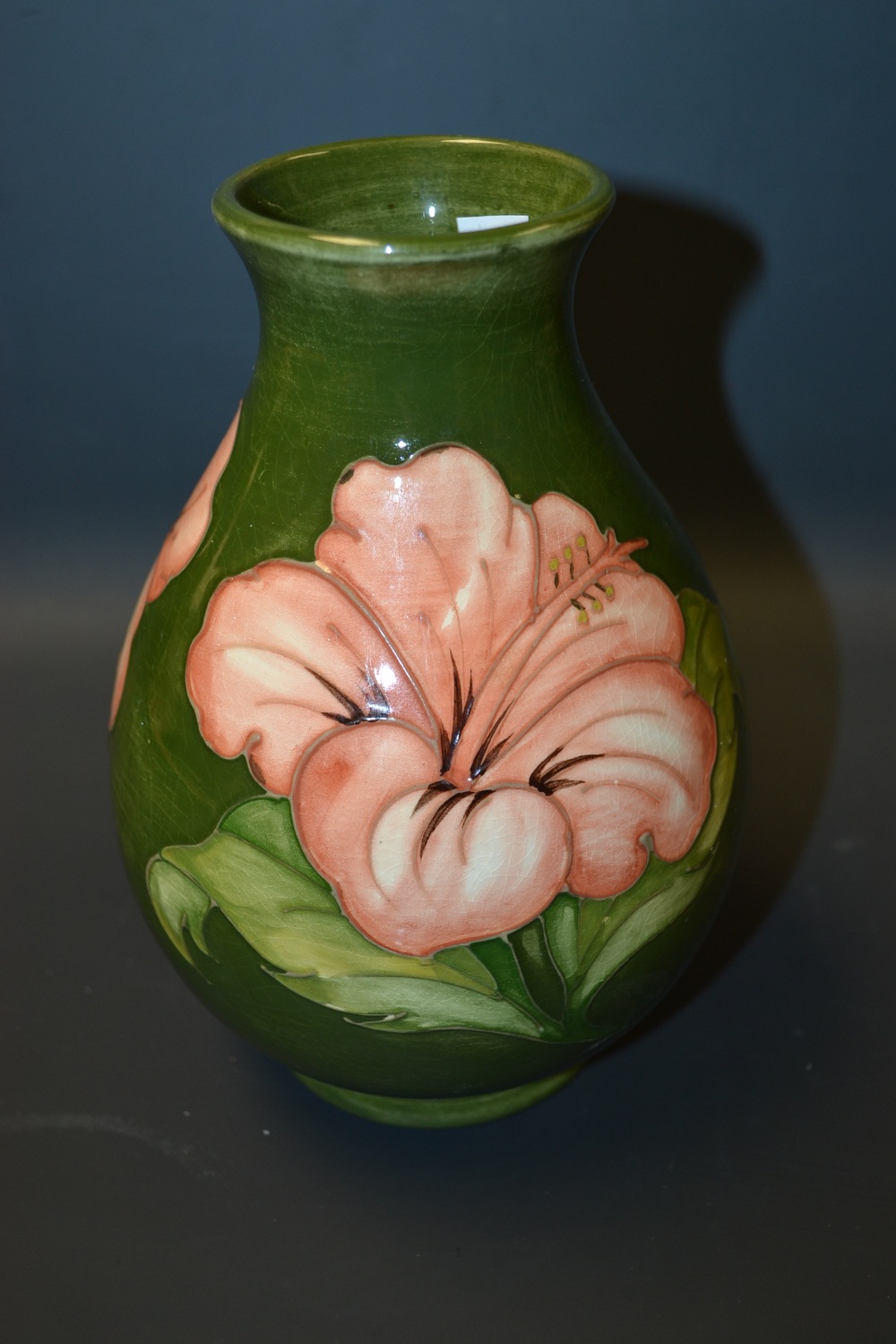 A Moorcroft Pottery baluster vase, decorated in the Hibiscus pattern, green ground. impress and