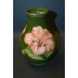 A Moorcroft Pottery baluster vase, decorated in the Hibiscus pattern, green ground. impress and