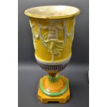 A Continental majolica urn, in relief with classical dancing ladies, fluted base, canted square