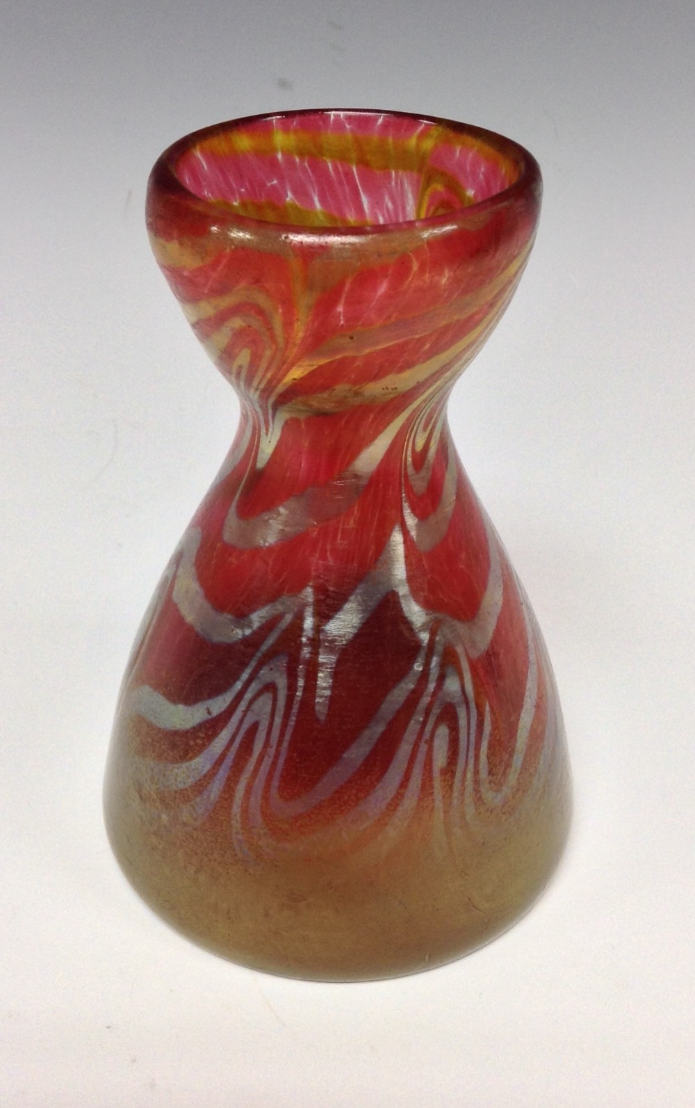 A Loetz style red iridescent conical flask glass vase, with gold and silver swirls, 11.5cm high