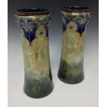 A pair of Royal Doulton cylinder vases, incised with flowerheads in shaped reserves,