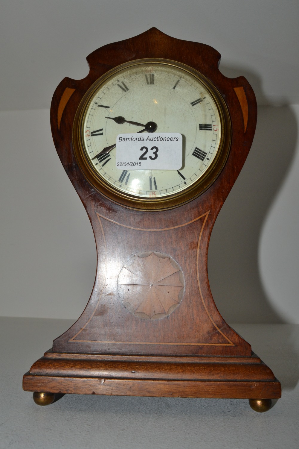 An Edwardian mahogany shaped balloon clock, the 8cm white enamel dial painted with Roman numerals,