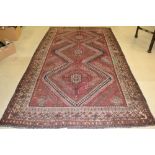 A shiraz carpet, woven in shades of burgendy and deep blue, 2.95m x 1.