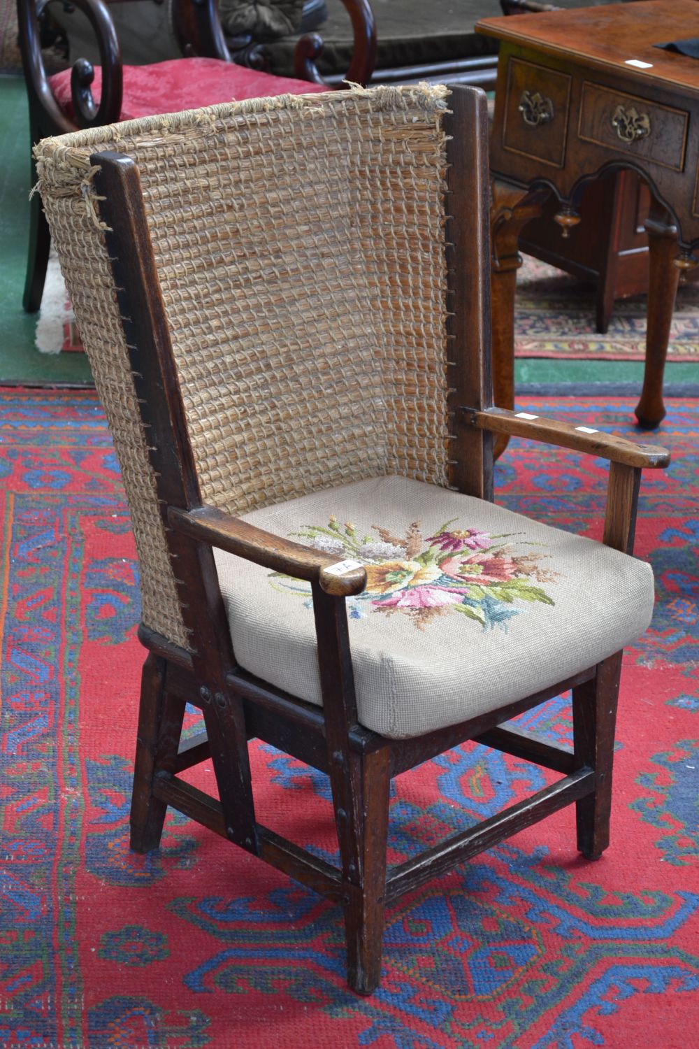 An oak Orkney chair, wrap around raffia back, tapestried stuffed over seat,