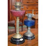 A Victorian cranberry glass and brass oil lamp; another,