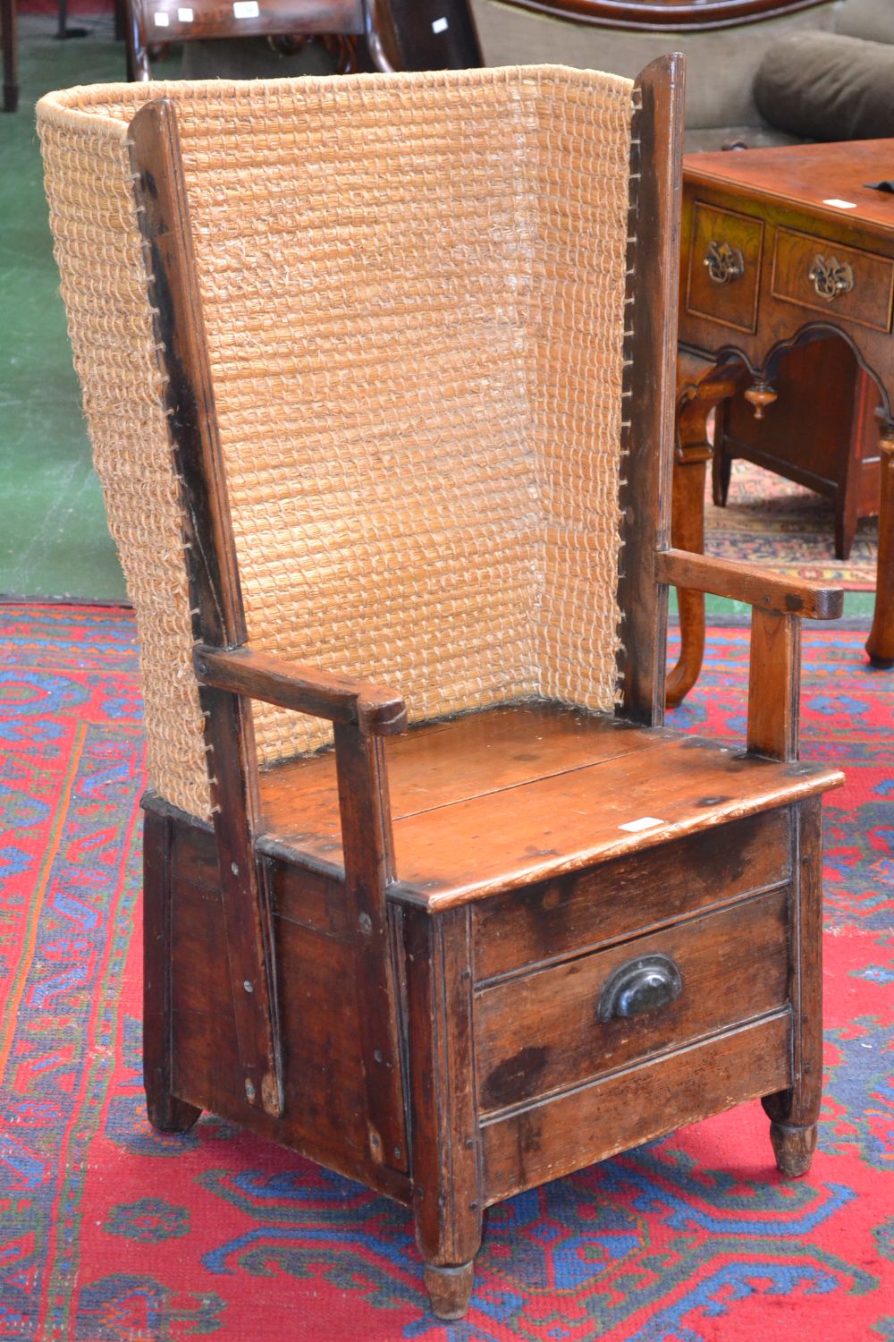 A pine Orkney chair, wrap around raffia back, open arms with scrolling terminals,