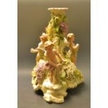 A German table centrepiece, the stand with three cherubs each standing, encrusted with hyacinths,