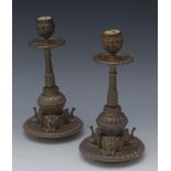 A pair of 19th century bronze candlesticks, urnular sconces, broad drip pans,
